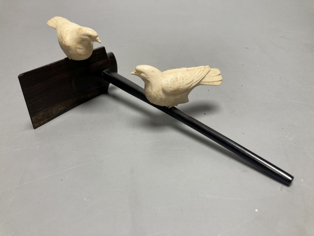 A Japanese ivory group of two carved doves, resting on a hardwood perch, length 21cm